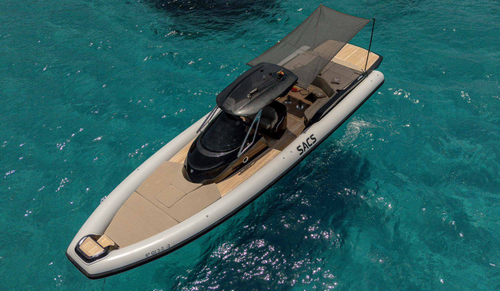 Luftaufnahme eines luxuriösen aufblasbaren Schnellboots mit Sonnendach, das auf klarem türkisfarbenem Wasser schwimmt und über gepolsterte Sitze sowie eine elegante schwarze Konsole verfügt.